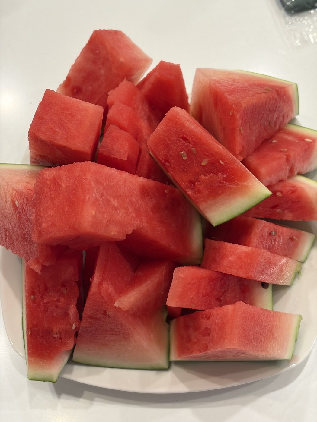A pile of watermelon chunks stacked loosely on a white plate