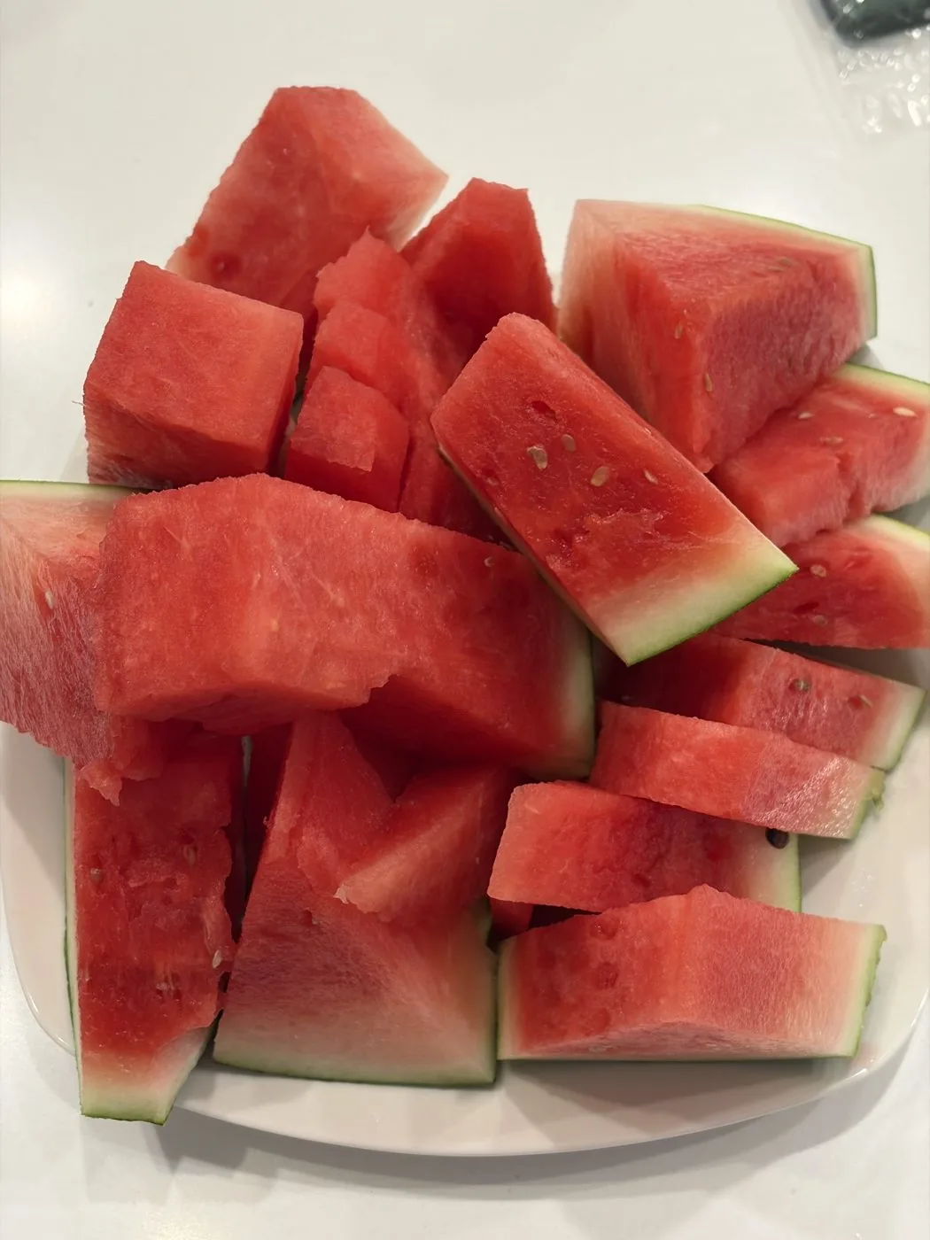 A pile of watermelon chunks stacked loosely on a white plate